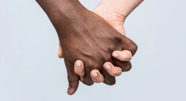Karışık ırk çifti el ele tutuşuyor. Siyah beyaz el aşk ortaklığı. Beyaz kadın, Afrikalı adam el ele tutuşan arkadaşlık sembolü..