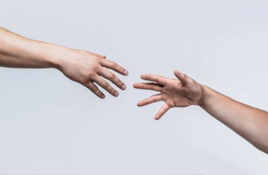 Gri arka planda birbirine doğru uzanan iki erkek el. Uzanmış, izole edilmiş bir kol, kurtuluş. Yardım elini kapat. İki el, silah arkadaşına yardım, takım çalışması. Yardım eli..