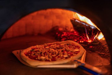 Pizza küreği, fırında hamur pişirme. Fırın küreğiyle fırında pişen pizzayı kontrol ederken pizza. Pizza konsepti. Geleneksel İtalyan pizzası hazırlıyorum..