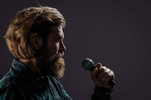 Человек-караоке певец. Бородач поет с микрофоном. Человек с бородой, держащий микрофон и поющий.