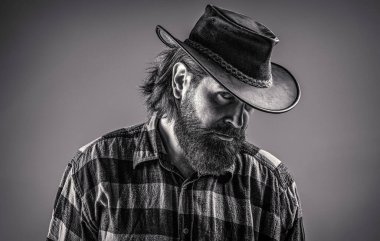Deri kovboy şapkası. Kovboy şapkasını ayarlayan yakışıklı genç adam. Tıraşsız kovboylar. Amerikan kovboyu. Ekose gömlekli kovboy tarzı. Siyah ve beyaz.