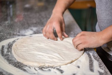 Eller pizza yapmak için hamur yoğurur. Pizza, makarna, sahip, molho ve risotto. Pizza hamuru yuvarlanıp yoğuruluyor. Hamur yoğuran elleri pişir, beyaz buğday unu serpiştir..