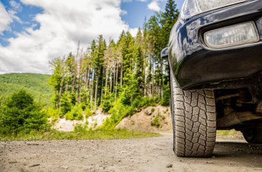 Dağlarda off-road araba, off-road seyahat ve sürüş konsepti. Büyük arabayla seyahat konsepti. Off-road Wheel 'in yakın çekimi. Bozkır arazisindeki araba tekerleğine yakın çekim. Dağ yolunda off-road.