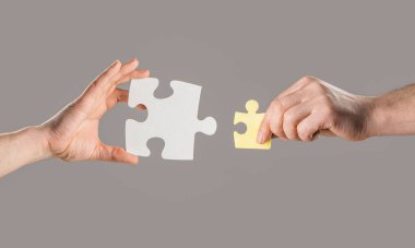 Erkekler farklı renk yapboz parçalarını birleştiriyor. Takım çalışması konsepti. İnsan eli, yapboz parçalarını bir araya getiriyor. İşadamı kurumsal istihdam, farklılık veya işbirliği stratejisi verdi.