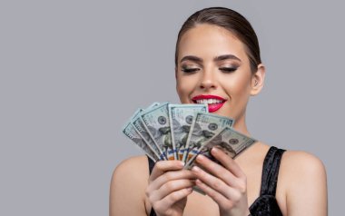 Yüzünde bir gülümseme olan kız çok dolar sayar. Dolar olarak çok para tutan bir kadın. Lüks, güzellik ve para konsepti. Elinde dolar, banknotlar olan bir kadın..