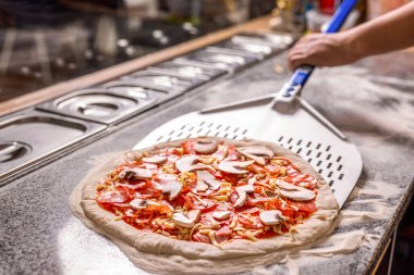 Şef elinde kürekle pizza hazırlar. Çiğ pizza pişirmeye hazır. Mutfakta elinde kürekle yemek pişiriyor. Adam pizza hazırlıyor. Pişiren el pizza yapar..