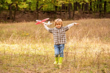 Uçağı olan küçük bir çocuk. Küçük çocuk pilot olmayı hayal ediyor. Çocuk oyuncak uçakla oynuyor. Mutlu çocuk oyunu. Mutlu çocuk dışarıda oynuyor. Mutlu çocuk uçakla oynuyor..
