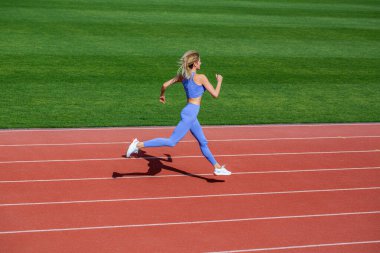 Spor giyimli bir kadın stadyumda koşuyor. Dişi koşucu dışarıda koşuyor, koşucu. Stadyumda spor yapan kadın. Stadyumda koşan genç fitness kadın koşucusu.