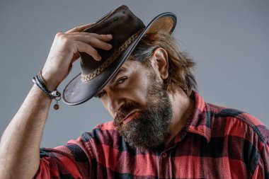 Deri Kovboy Şapkası. Kovboy şapkası takan genç bir adamın portresi. Şapkalı kovboylar. Yakışıklı sakallı maço. Tıraşsız kovboylar. Amerikan kovboyu.