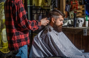 Hipster müşteri saçını kestiriyor. Berber dükkanını ziyaret eden adamlar. Hipster müşteri saçını kestiriyor. Saç makasıyla berber elleri. Clipper ile berber müşterinin ensesinde saç buduyor..