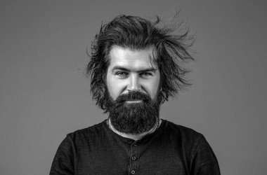 Sakallı, bıyıklı ve son moda saçlı yakışıklı bir erkek. Sakallı adam, şık saç stili, sakallı. Berber dükkanında erkek tıraşı. Siyah ve beyaz.