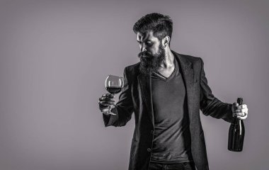 Şişede kırmızı şarap, şarap kadehi. Takım elbiseli adam köpüklü kırmızı şarapla kadeh kaldırıyor. Siyah ve beyaz.