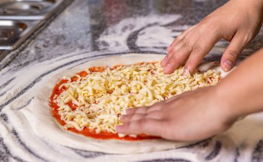 Teknede duran ve pizza hamuruna domates soslu peynir serpiştiren adama yakın çekim. Masada pizzaya peynir ekleyen adam, yakın plan. Aşçı mutfakta. Pizzanın malzemelerini koyuyor..