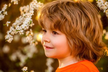 Çocuk, çocuk, bahar, güneş. Bahar bahçesinde yürüyen mutlu küçük çocuk. Küçük çocuk dışarıda yürüyor, bahar havası, güneş parlıyor, çocuk güneşin altında dinleniyor..