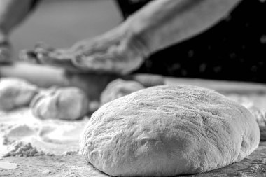 Hamur, el. Kadın mutfak masasına hamur saçıyor, kapat. Siyah ve beyaz.