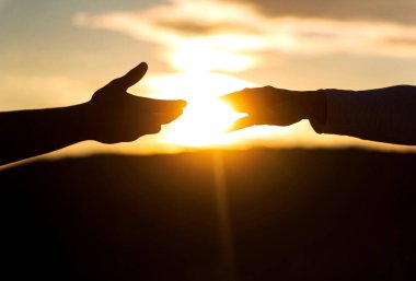 Gökyüzü arka planında iki el silueti, bağlantı ya da yardım kavramı. Uzanmış eller, kurtuluş, siluete yardım, konsept yardım. Yardım eli uzatıyorum. Kurtarma, yardım jestleri veya eller.