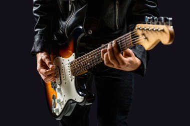 Siyah arka plandaki bir adamın elinde elektro gitar. Gitar çalan adam. Elektro gitar çalan bir müzisyenin elleri. Elektro gitar, gitarist, müzisyen rock. Rock grubu iş başında.