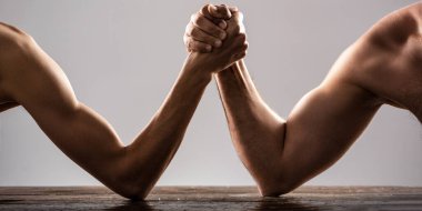 Bilek güreşi. Çok kaslı bir adam zayıf bir adamla bilek güreşi yapıyor. Zayıf elle bilek güreşi, stüdyoda güçlü bir kol. İki adam bilek güreşi yapıyor..