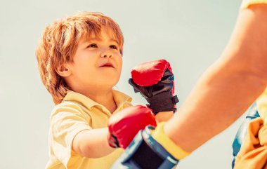 Baba oğlunu boks eğitiyor. Boks antrenörü ve boks eldiveni giyen küçük bir çocuk. Boks antrenmanında küçük sporcu çocuk. Sporcu boks eldivenli küçük çocuğa koçluk yapıyor..