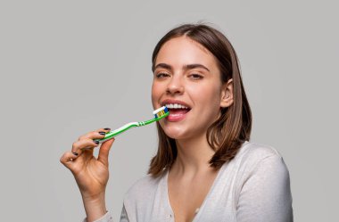 Elinde diş fırçası tutan gülümseyen sevimli bir kadının portresi. Elinde diş fırçası tutan güzel dişleri olan gülümseyen bir kadın. Diş sağlığı geçmişi. Diş fırçasıyla mükemmel ve sağlıklı dişleri kapat..
