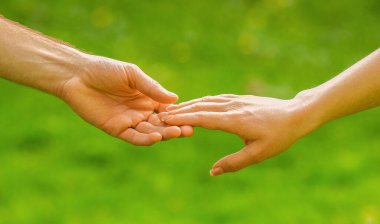 Dışarıda, çim tarlasında el ele tutuşan genç çift. Eller, çiftler. Çiftler sonbaharda ya da yaz parkında el ele tutuşurlar. Yürürken el ele tutuşan çiftlerin yakınlaşması..