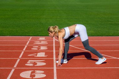 Sporcu başlıyor. Genç sporcu kadın stadyumdaki açık hava pistinde koşuyor. Başlangıçtaki kız koşmaya ve kazanmaya hazır. Atletizm pistinde tek başına koşan bir bayan atlet..