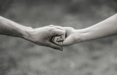 Takım çalışması arkadaşlığı. Kurtarma jesti ya da güçlü eller. Erkek ve kadın doğaya karşı el sıkışıyor. Siyah ve beyaz.