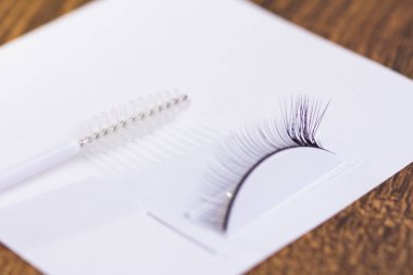 Yapay kirpiklerdeki eklentiler ve beyaz bir çarşaftaki kirpik fırçası