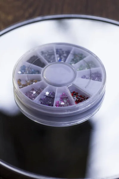 Box with rhinestones for manicure and makeup on a mirror background