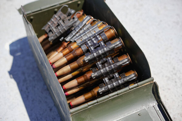 Close up shot of a machine gun belt loaded with cartridges, in an ammo box.