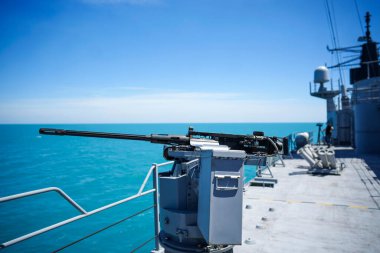 Color image of an automated machine gun on the deck of a military ship, at sea.