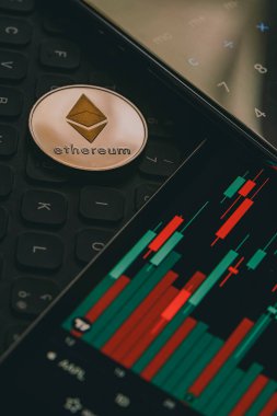 Mum çubuğu grafik çizelgesi ve dijital hesap makinesi olan bir monitörün yanındaki Ethereum kripto para birimini kapat.