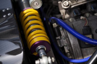 Close up shot of a yellow motorcycle shock absorber with metallic springs.