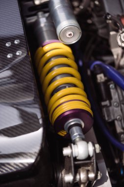 Close up shot of a yellow motorcycle shock absorber with metallic springs.