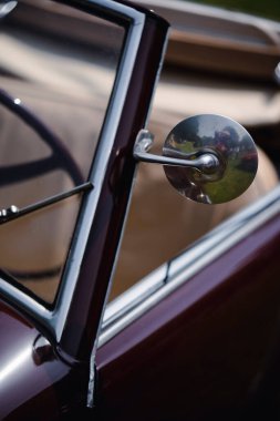 Close up shot of a round rear view mirror on a vintage car. 