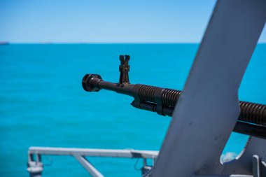 Color image of an automated machine gun on the deck of a military ship, at sea.