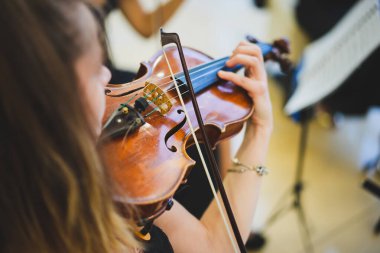 Toplum içinde keman çalan tanınmayan bir kadının detaylı görüntüsü.