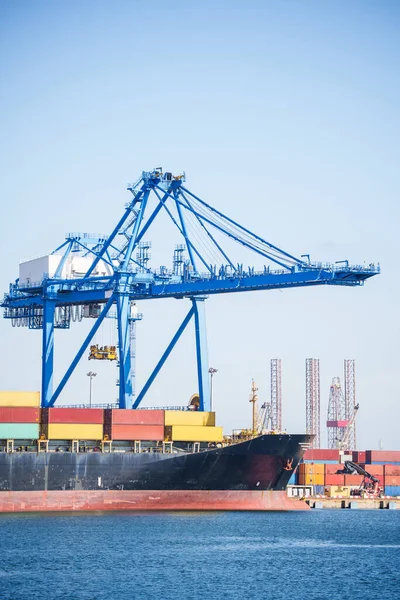 Color image of a container terminal, with cranes, in a commercial port.