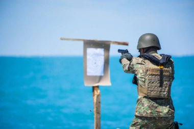 Kamuflaj üniforması giymiş bir askerin bir hedefe silah ateşlemesinin renkli görüntüsü..