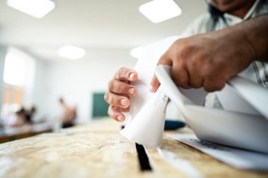 Seçimler sırasında sandıkta oy kullanırken bir kişi sandığa oy veriyor.