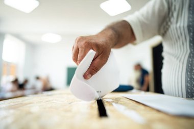 Seçimler sırasında sandıkta oy kullanırken bir kişi sandığa oy veriyor.