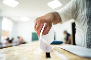 Seçimler sırasında sandıkta oy kullanırken bir kişi sandığa oy veriyor.