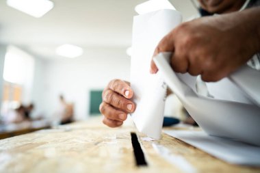 Seçimler sırasında sandıkta oy kullanırken bir kişi sandığa oy veriyor.