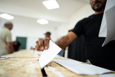 Seçimler sırasında sandıkta oy kullanırken bir kişi sandığa oy veriyor.