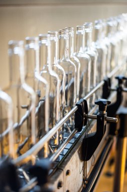 Bir içki şişeleme fabrikasında, taşıyıcı banttaki boş cam şişeler..