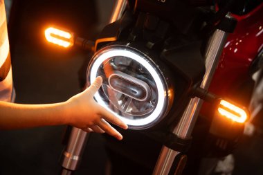 Modern bir motosiklet LED farına dokunan bir çocuğun yakın çekimi.