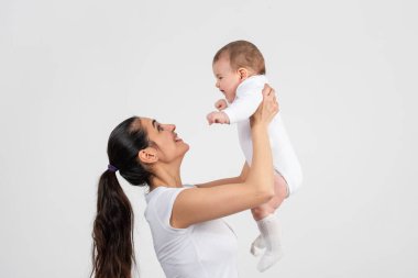 Güzel genç anne beyaz arka planda sevimli bebeğiyle eğleniyor. Yüksek kalite fotoğraf