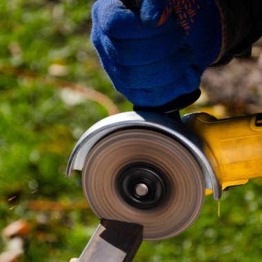 Ağır endüstri işçisi araba servisinde çeliği öğütücüyle kesiyor. Açı öğütücü kullanan bir inşaat işçisi bir sürü kıvılcım üretir.