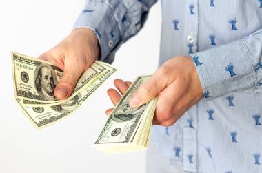 dollars in the hands. Businessman in blue shirt counts bills for 100 dollars