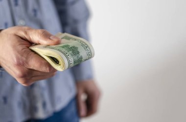 A thick pack of dollars in the hands of a man. A man gives a bribe.